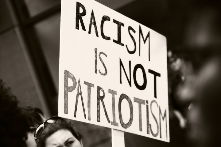 Das Foto zeigt ein Demoplakat, auf dem steht: "Racism is not Patriotism"